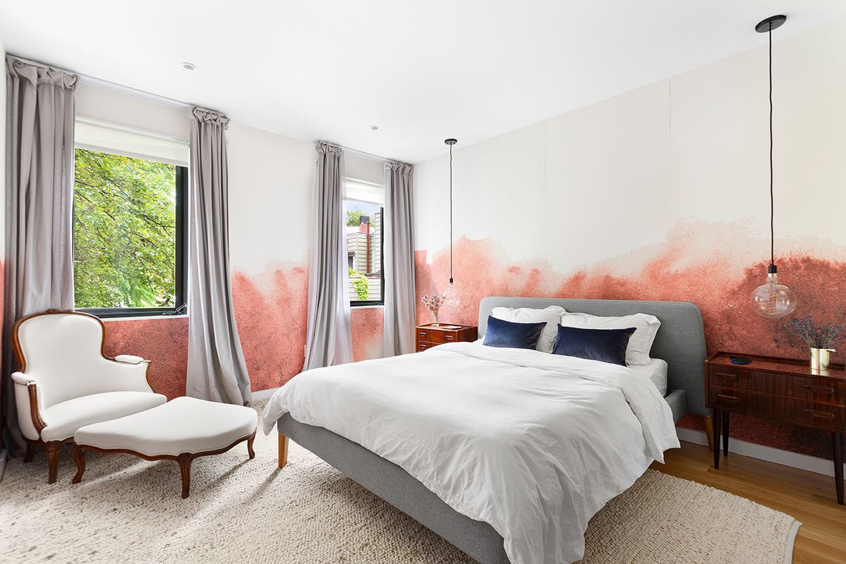 Furnished rental with pink walls and a white bed, and large white accent lounge chair.